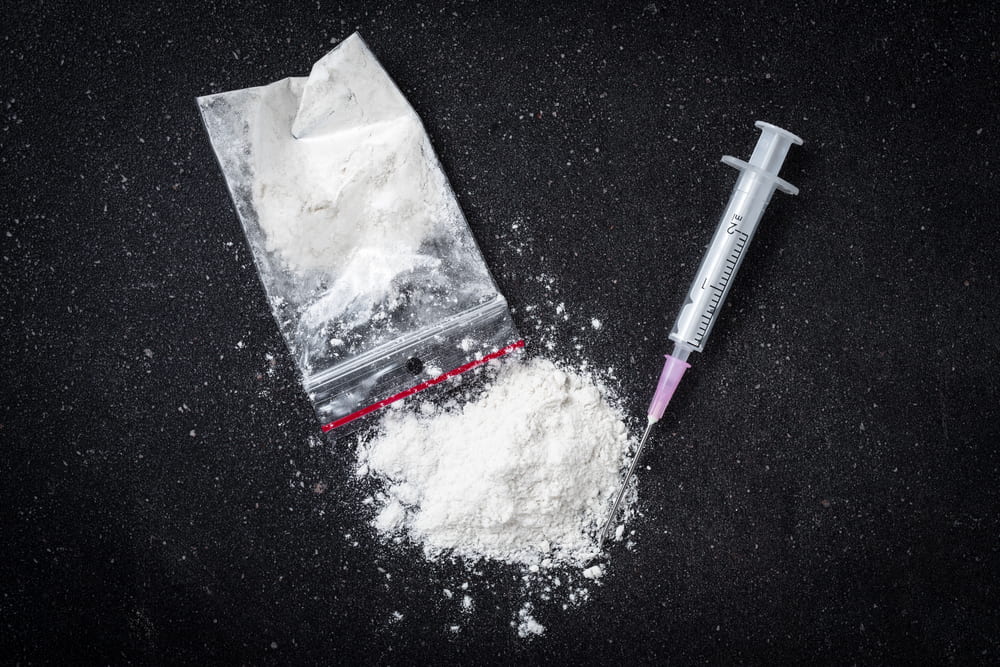 A powdered drug alongside a syringe.